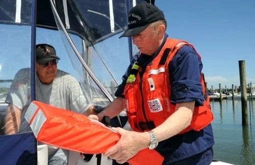 Räddningspersonal visar upp en orange flytväst ombord på en mindre båt